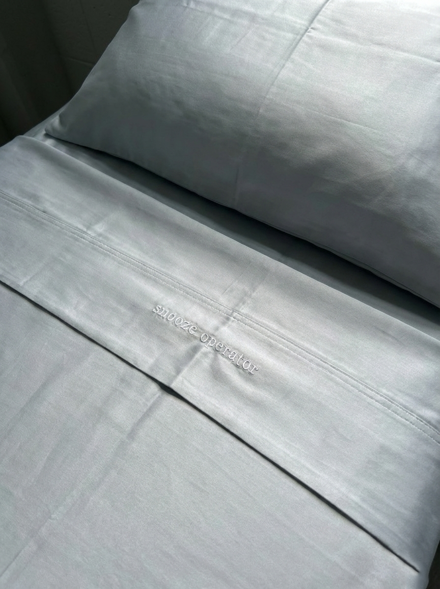 Twin XL fitted sheet from the Bedly Bamboo Bed Set secured over the corner of a dorm mattress